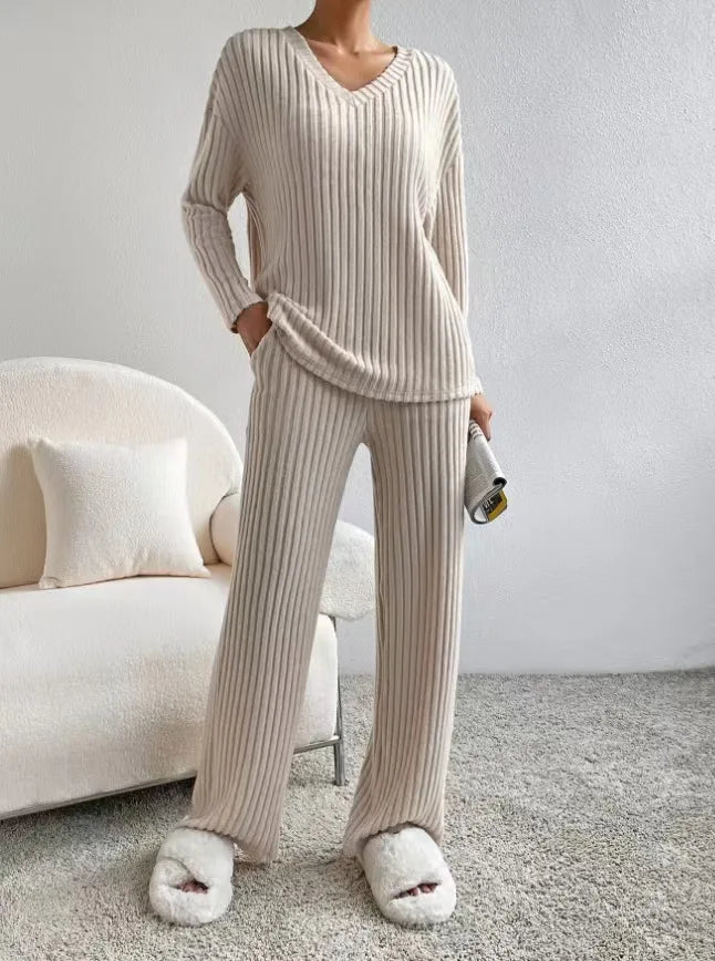 Person wearing a beige ribbed lounge set with matching slippers in a cozy room.