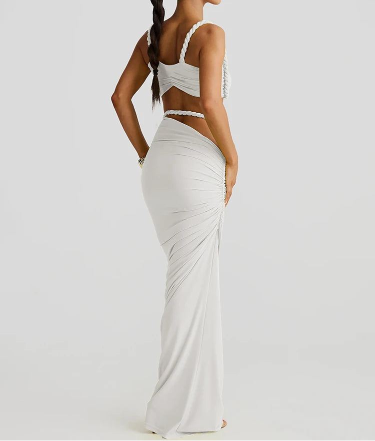 Woman wearing a white evening gown with cut-out design on a plain background