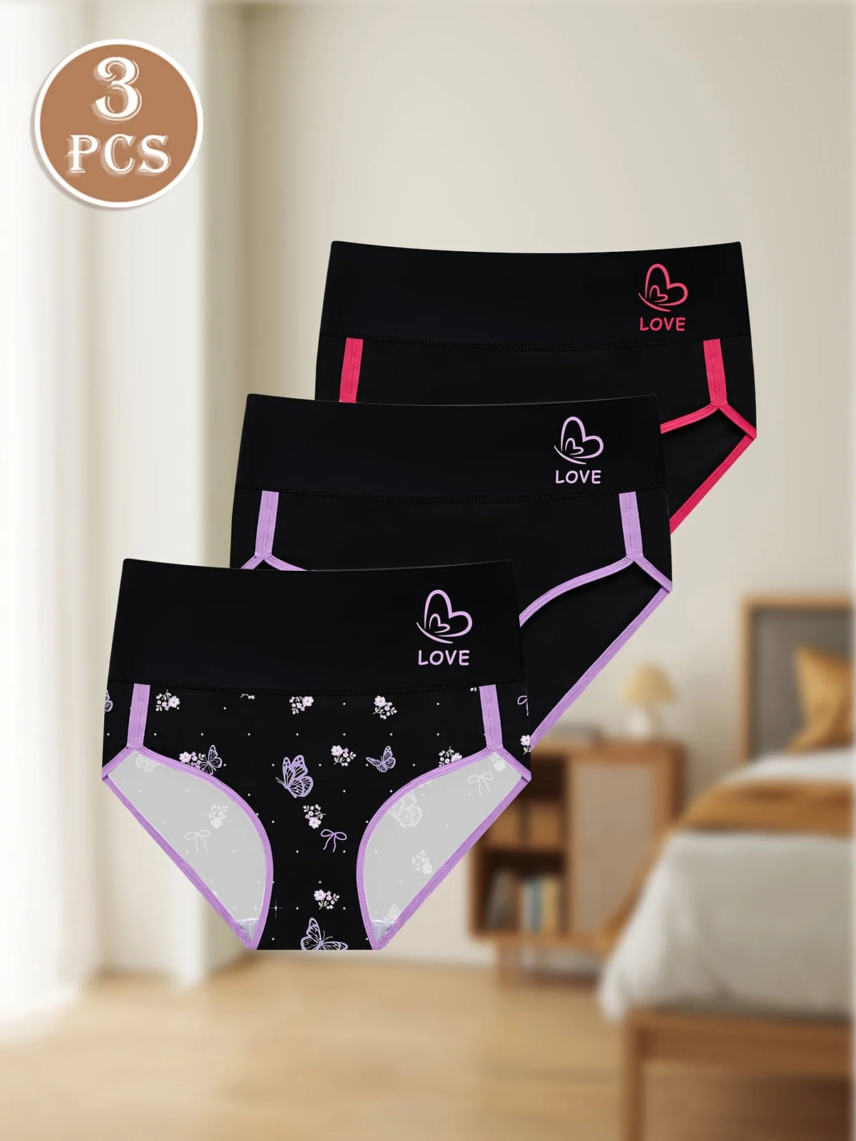 Three pairs of black underwear with pink accents on a neutral background
