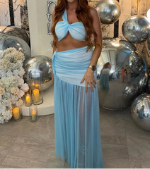 Woman in a light blue dress standing in an elegant indoor setting with decorative balloons and flowers.