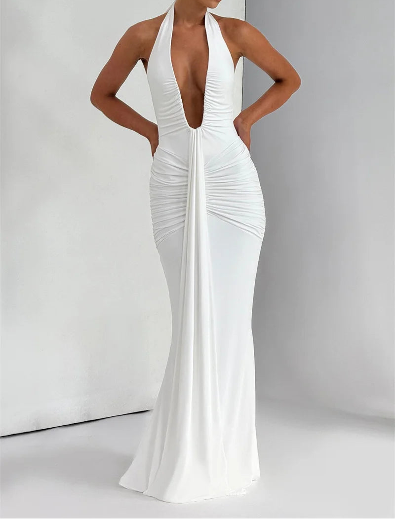 Woman wearing a white halter neck gown against a plain background