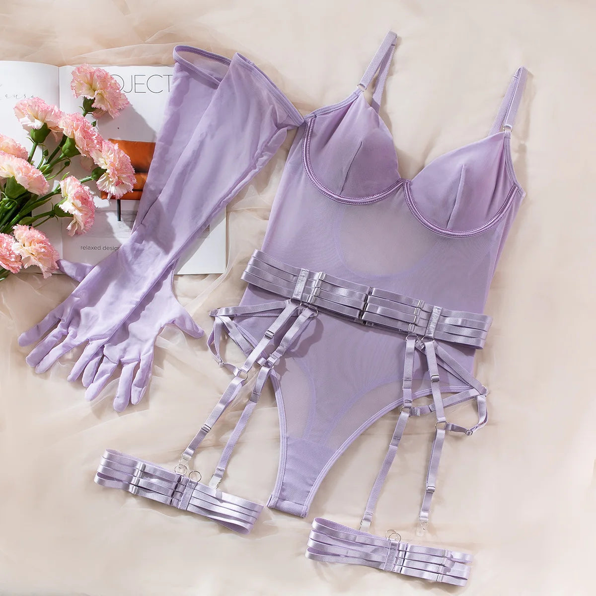 Lavender lingerie set with matching gloves on a light surface with flowers and magazine in the background.