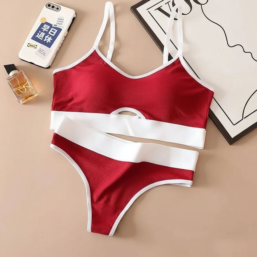 Red and white bikini set on a beige surface with a phone, perfume bottle, and framed picture.