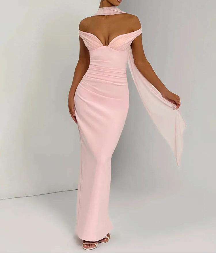 Woman wearing a pink off-shoulder gown with a sheer overlay against a white background