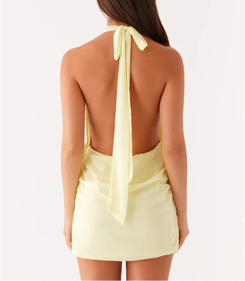 Woman wearing a light yellow halter top with a bow detail on a white background