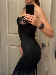 Person wearing a black dress with lace detailing in front of a door.