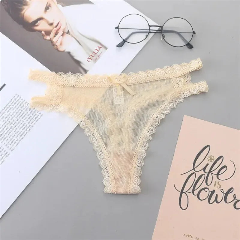 Beige lace thong on a gray surface with books and glasses in the background