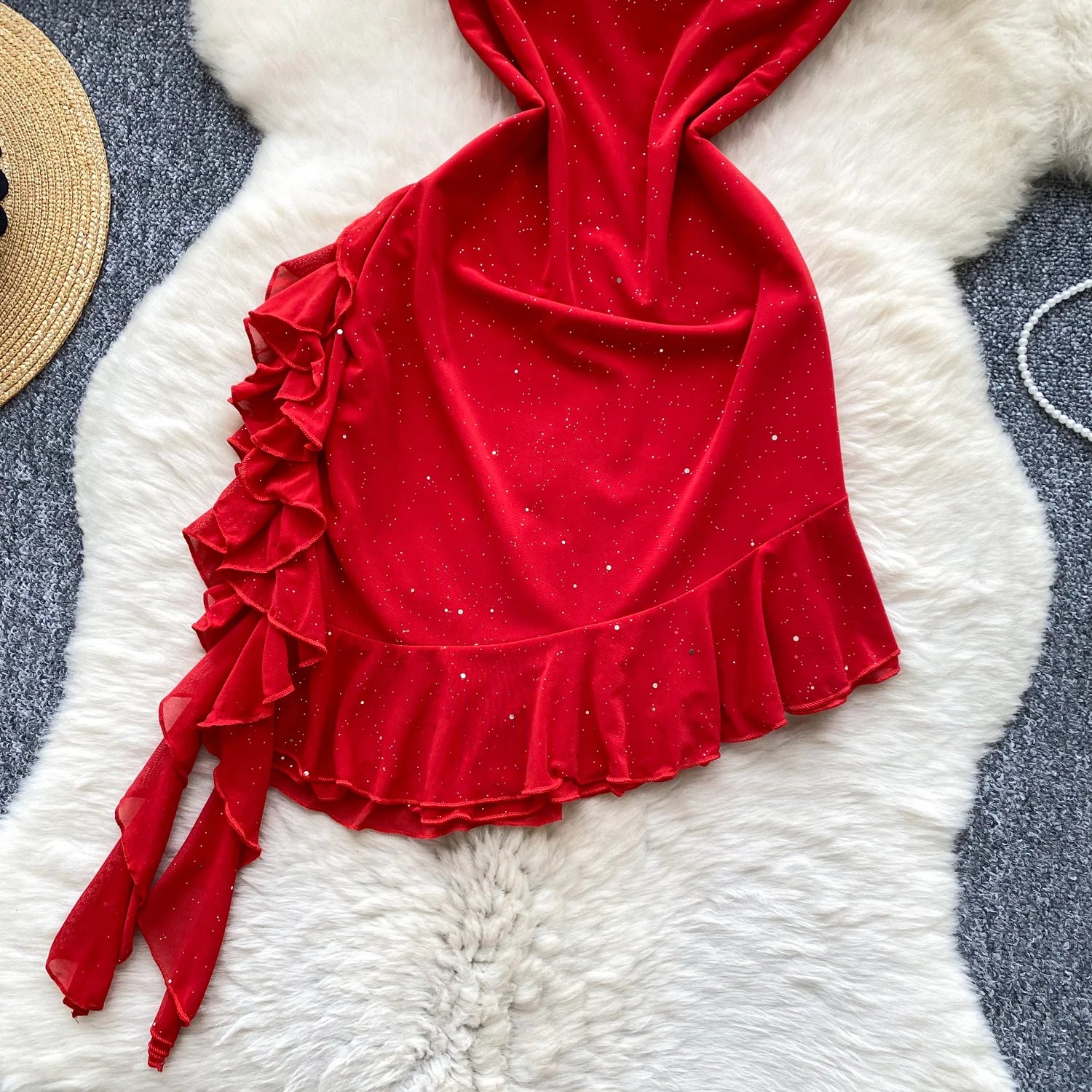 Red velvet top with ruffled details on a textured white surface