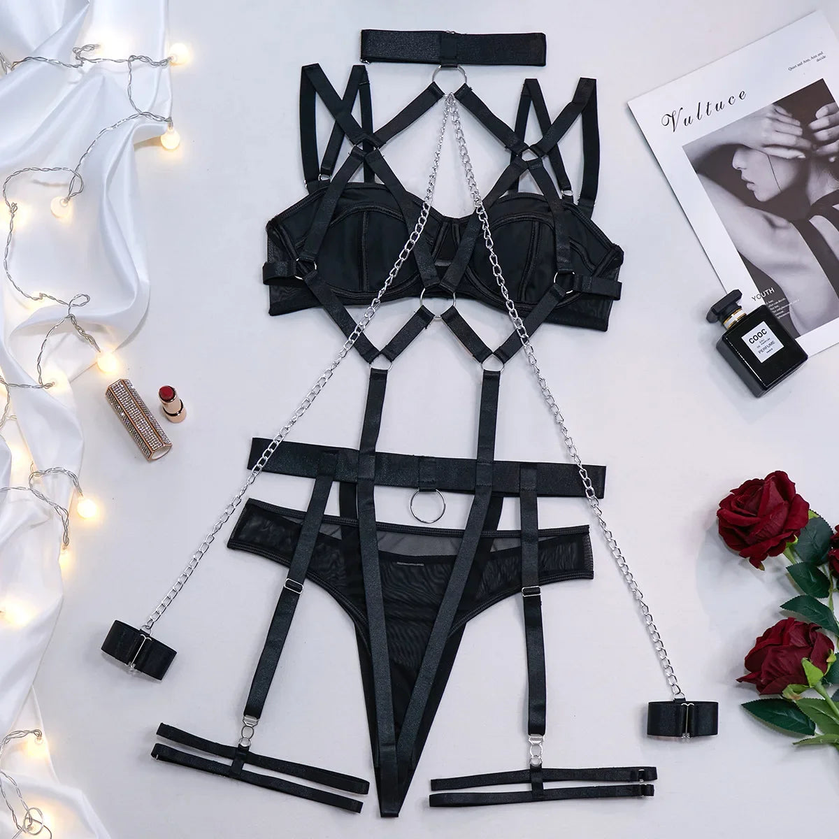 Black lingerie set with chains on a white surface with decorative elements.
