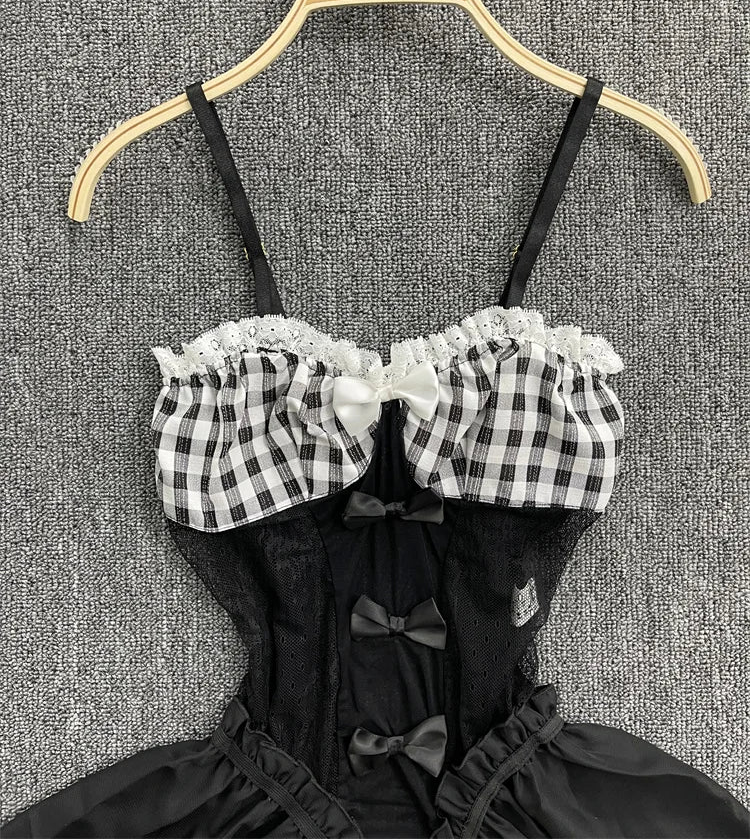 Black and white checkered top with lace details on a hanger against a textured gray background.