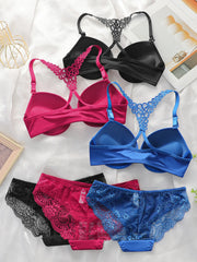 Four pairs of women's lingerie laid flat on a white fabric background: two bras at the top in black and pink, and two panties at the bottom in black and blue. Each bra is paired with matching lace-trim panties.