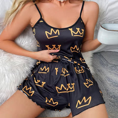 Black romper with gold crown patterns worn by a person on a soft surface.