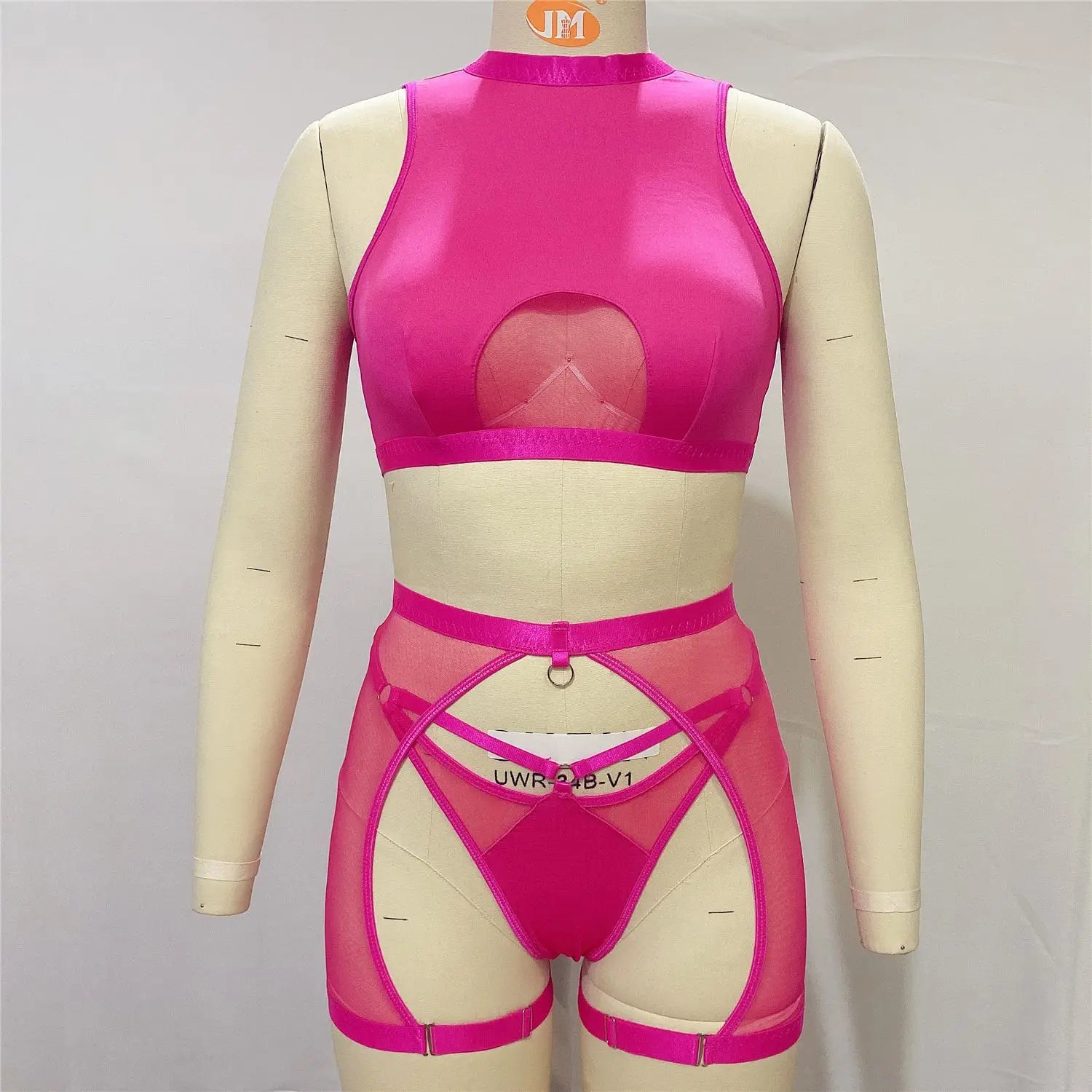 Mannequin wearing a pink mesh outfit with cut-out design on a plain background