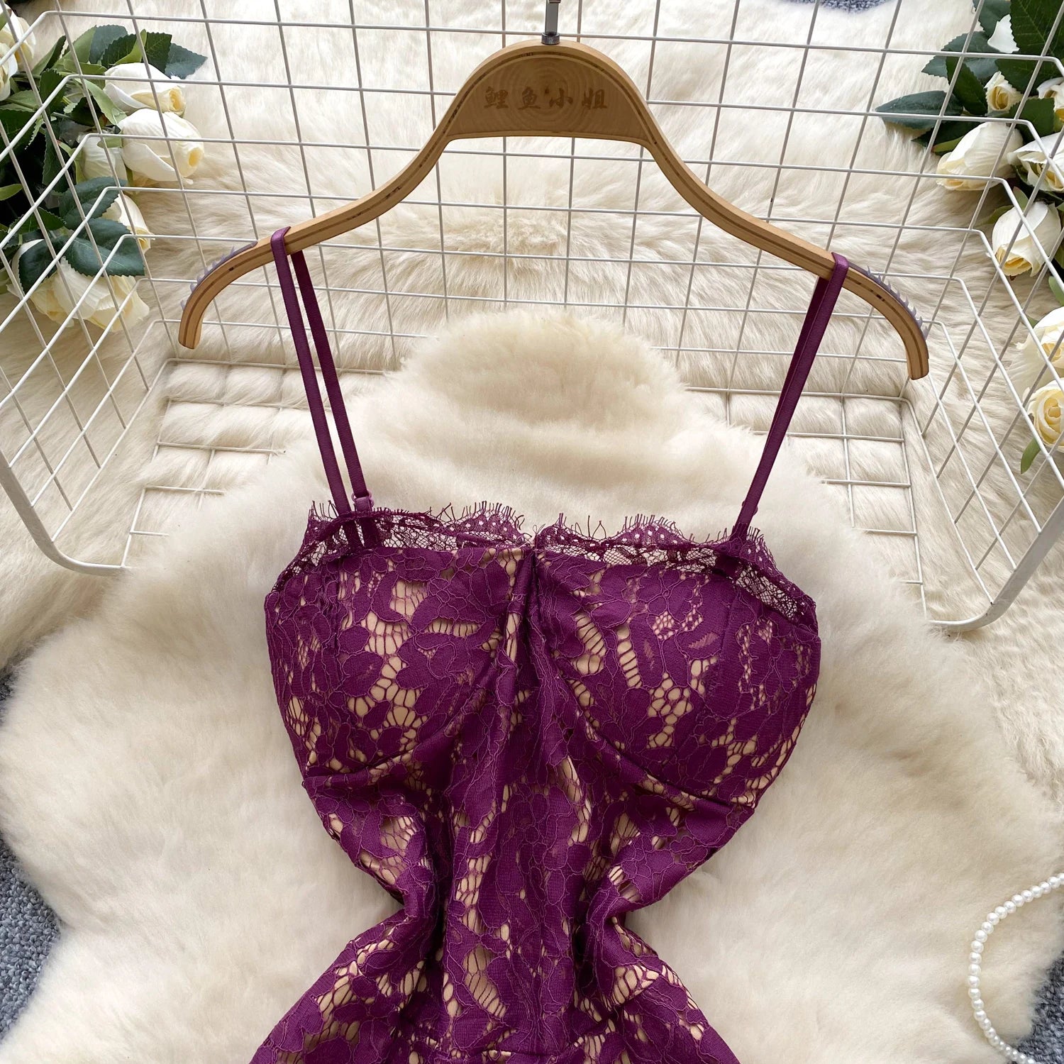Purple lace bra on a wooden hanger against a white fur background