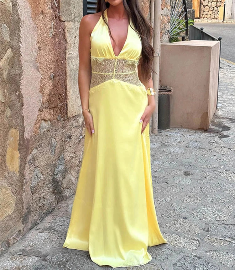 Woman in a yellow dress standing in an outdoor setting with stone walls.