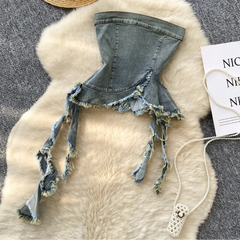 Denim bikini top with frayed edges on a fur surface with a hat and jewelry.