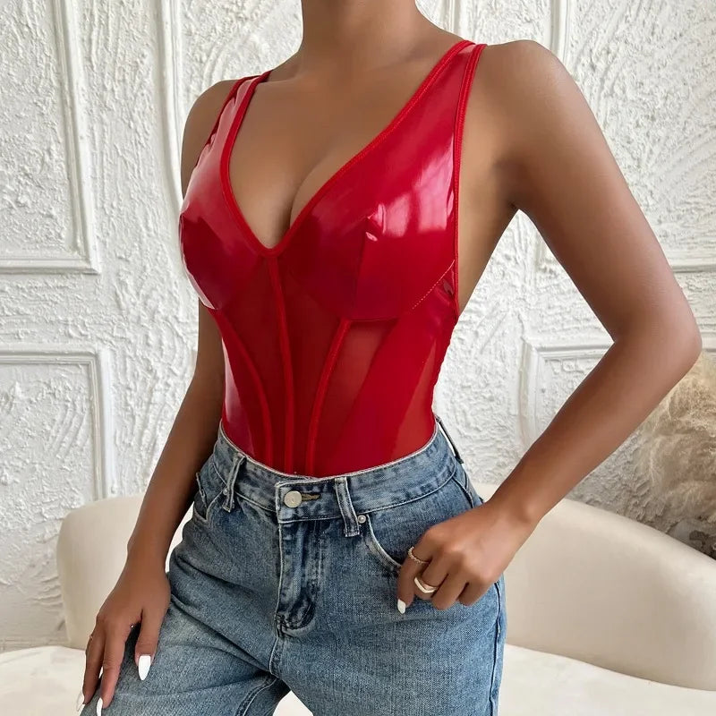 Person wearing a red latex top and blue jeans against a textured white wall.