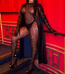 Person wearing a black lace outfit and sunglasses against a red curtain background