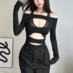Person wearing a black long-sleeve top with cut-out design and black pants on a plain background