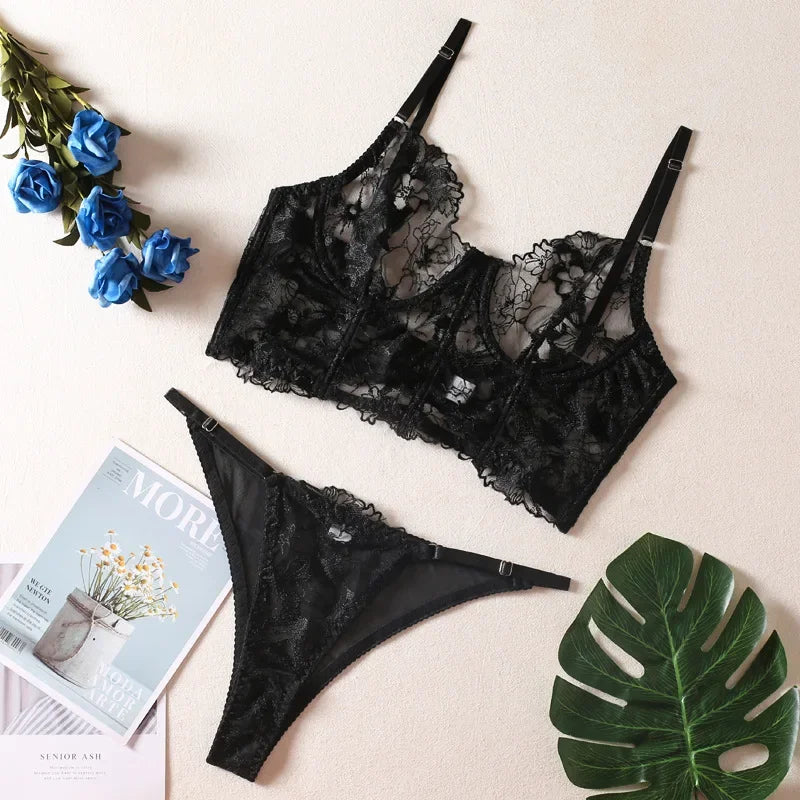 Black lace lingerie set with flowers and a magazine on a light background