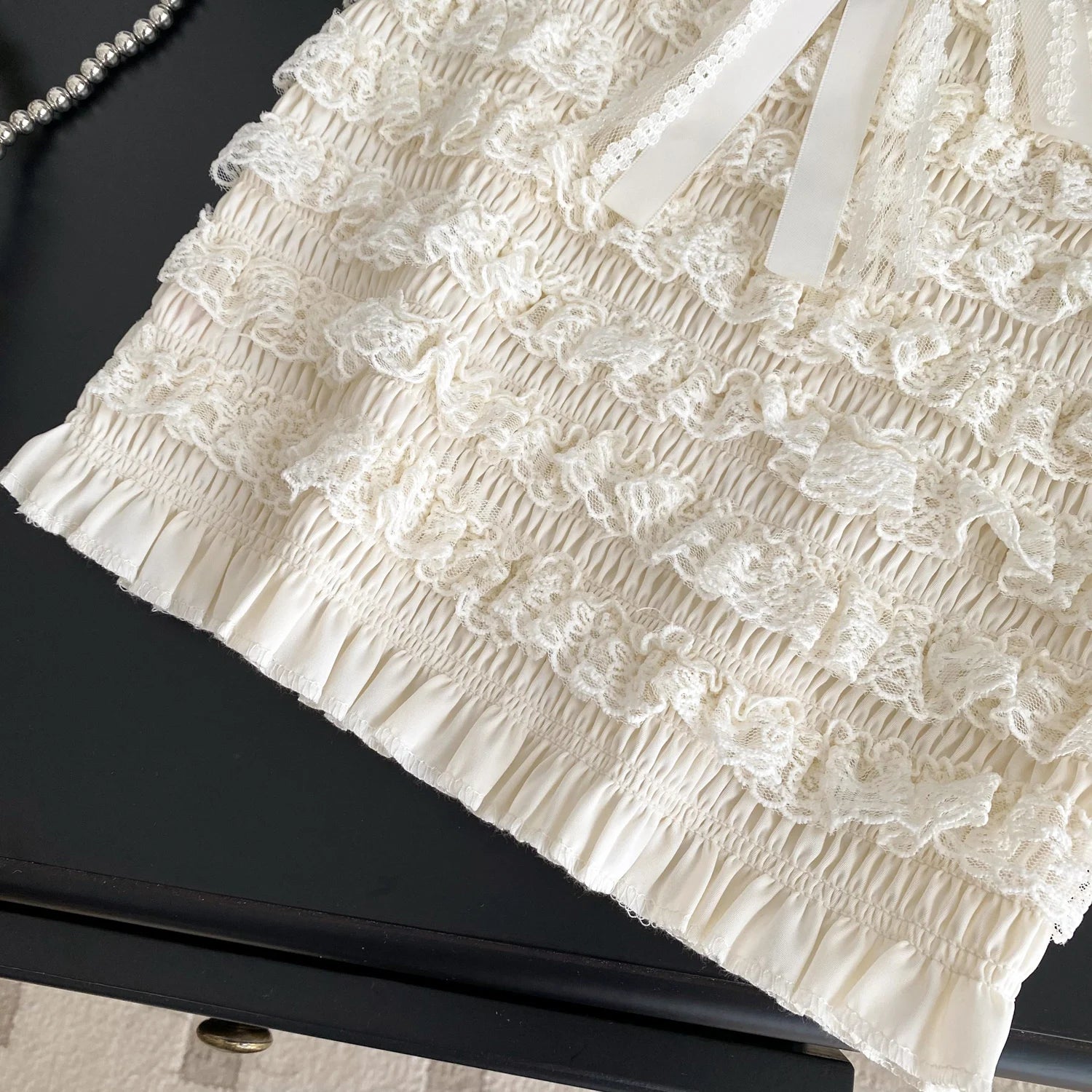 Close-up of a textured white fabric with floral patterns on a black surface.