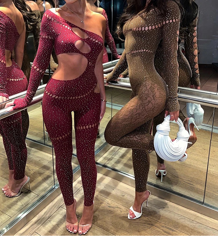Two women in sparkling bodysuits posing in a mirror.