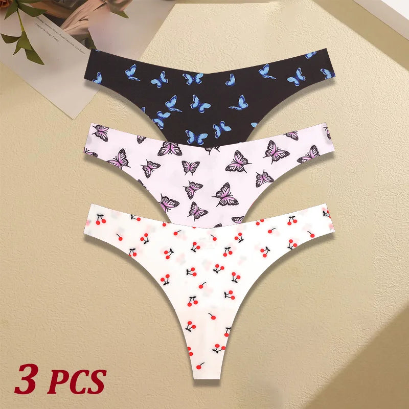Three pairs of women's underwear with butterfly, cherry, and black patterned designs on a beige surface.
