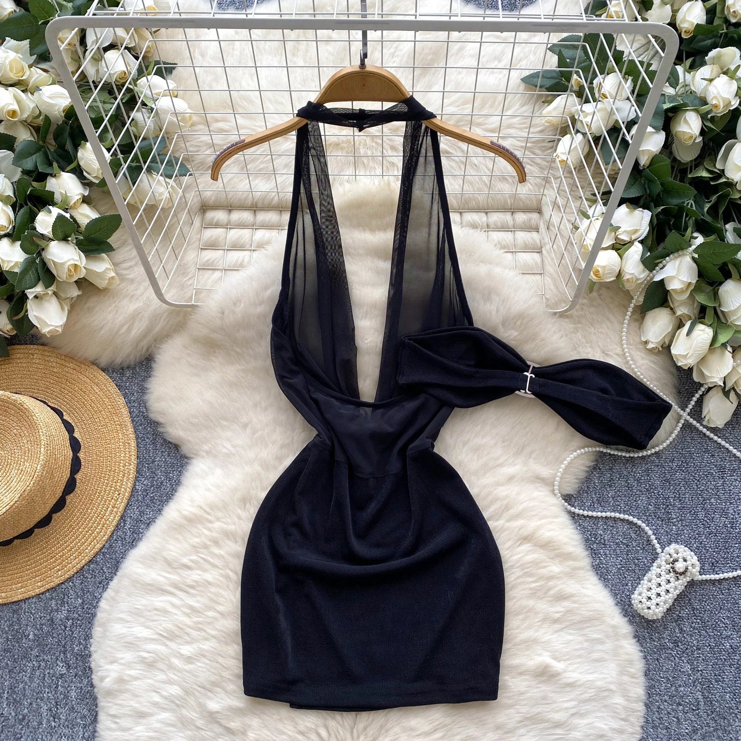 Black halter top with bow detail on a white fur rug with decorative elements.