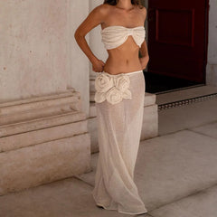 Woman wearing a beige strapless top and mesh skirt with floral details in an outdoor setting.