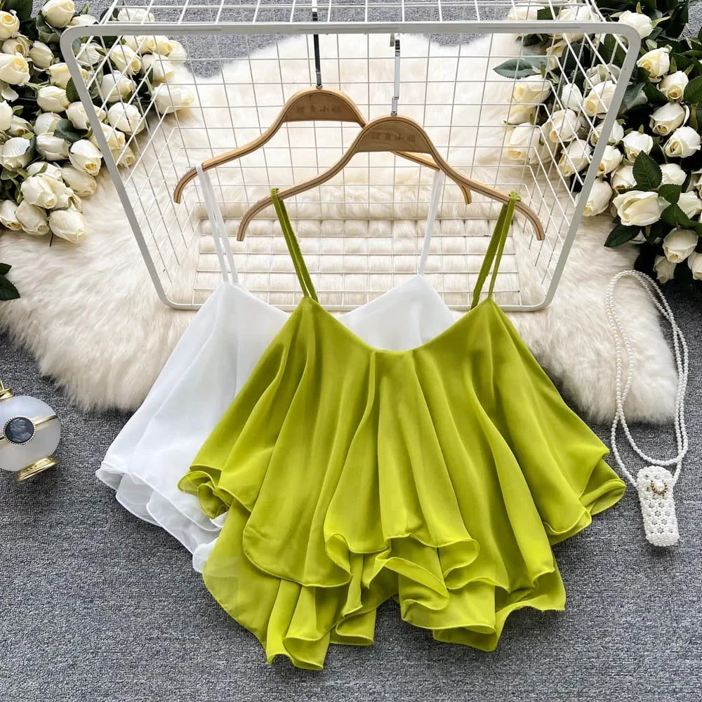 Green ruffled top on a hanger with flowers and a fluffy rug in the background