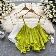 Green ruffled top on a hanger with flowers and a fluffy rug in the background