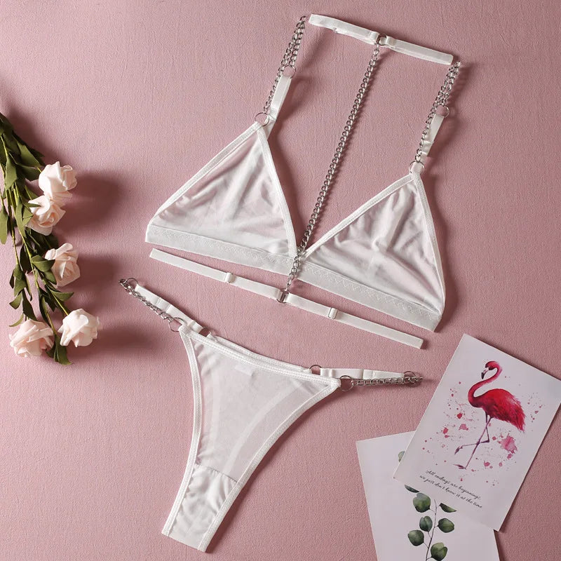 White bikini set with chain details on a pink background with flowers and cards.