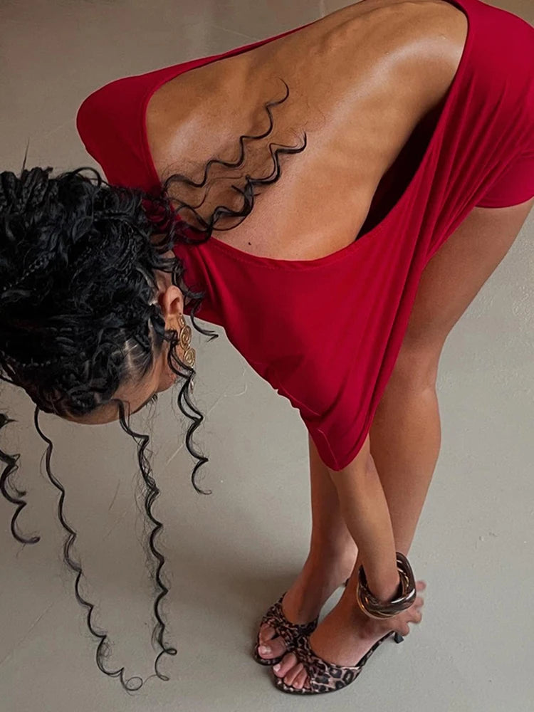 Woman in a red dress with a backless design, wearing leopard print sandals.