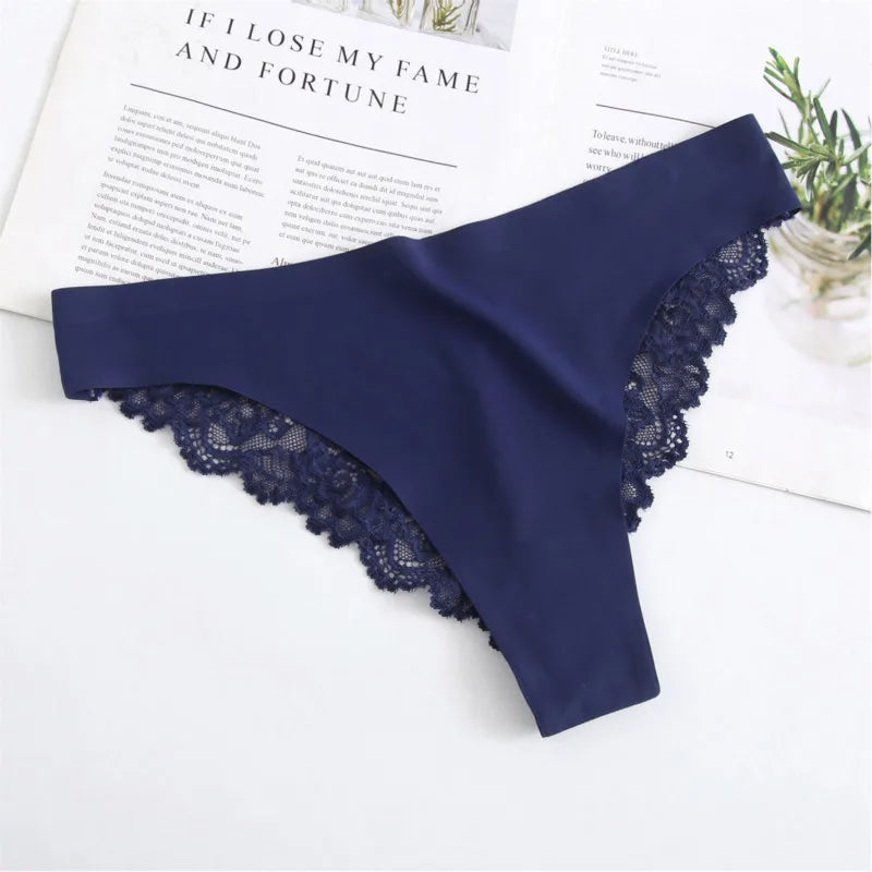 Navy blue lace thong on a white surface with a magazine in the background