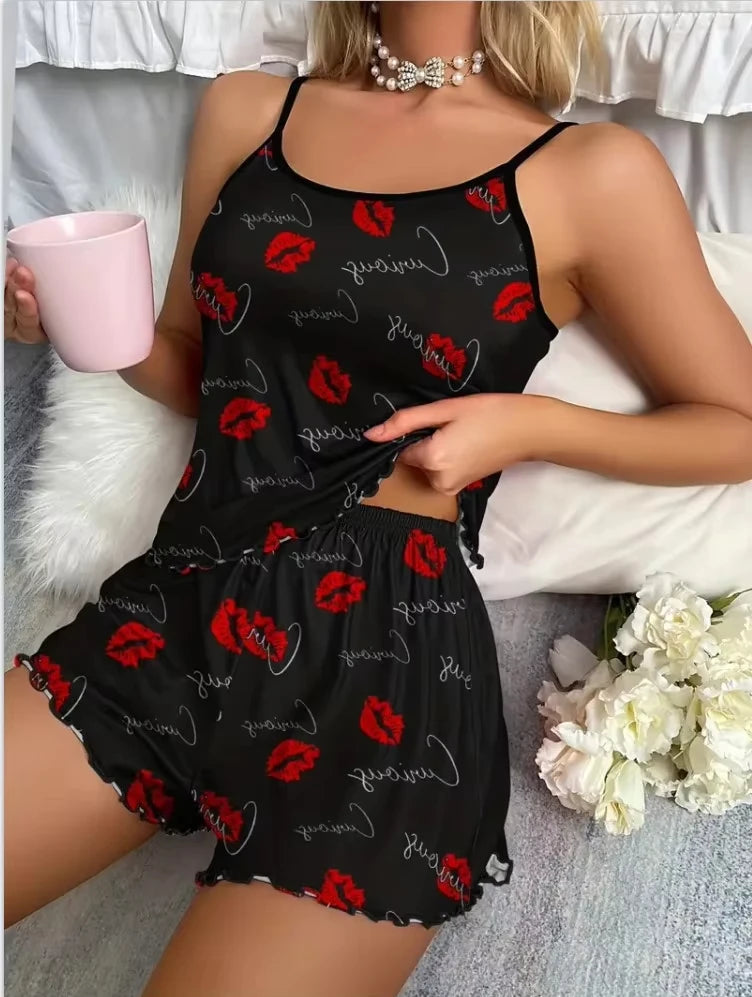 Person wearing a black pajama set with red lip prints, holding a pink cup on a white surface.