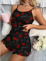 Person wearing a black pajama set with red lip prints, holding a pink cup on a white surface.