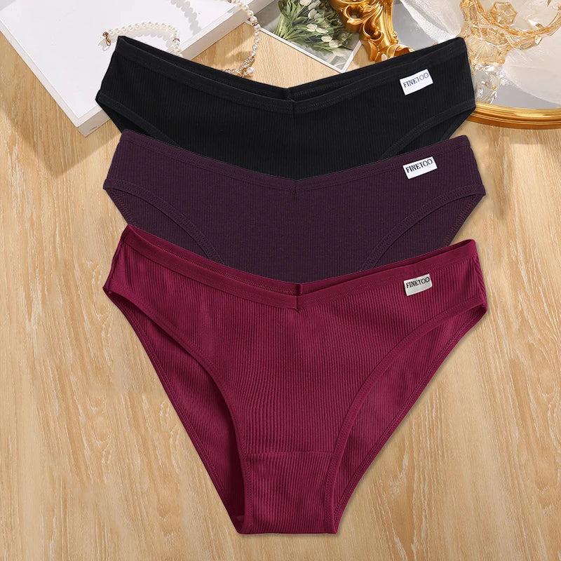 Three pairs of underwear in black, purple, and red on a wooden surface.