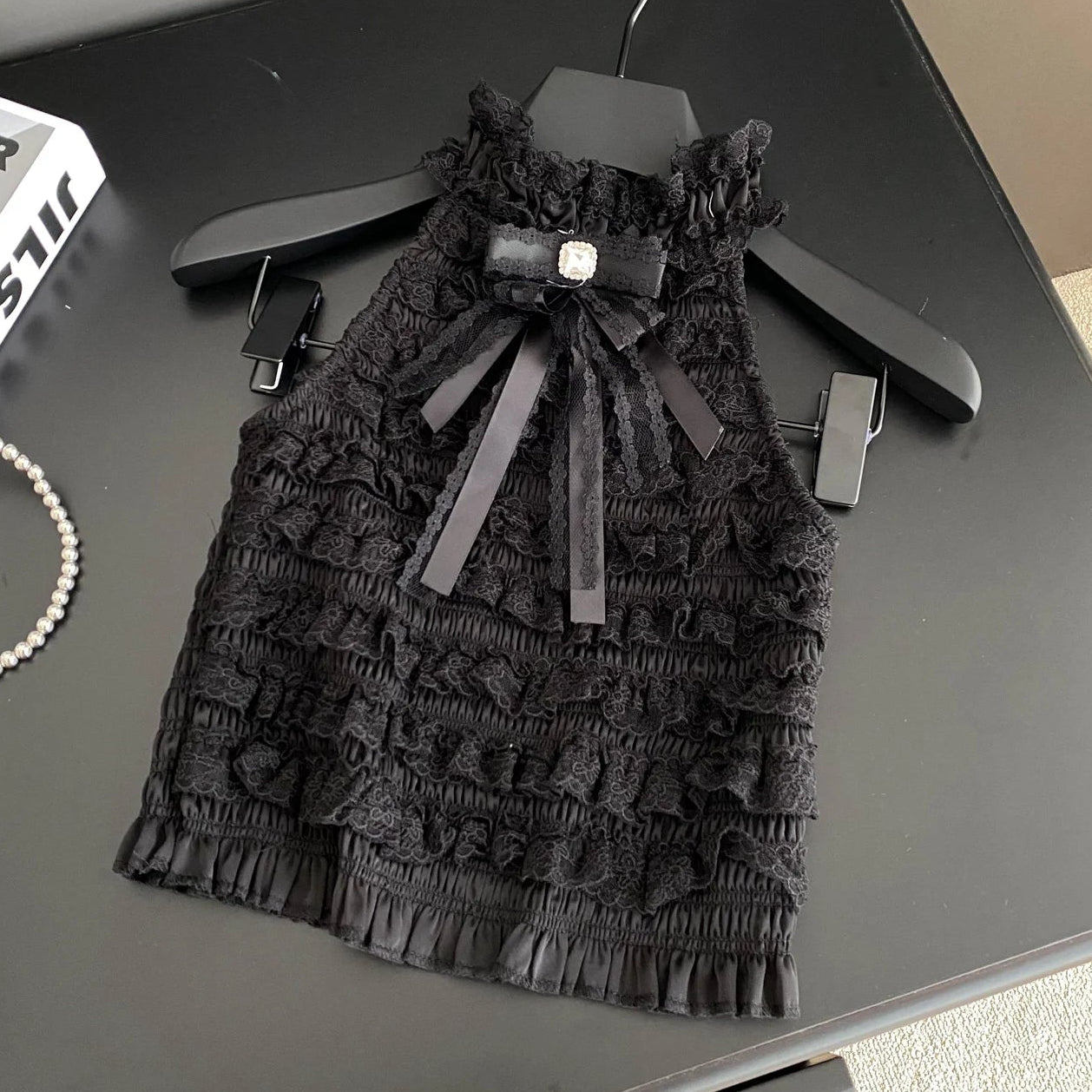 Black lace dress with a bow on a hanger on a dark surface