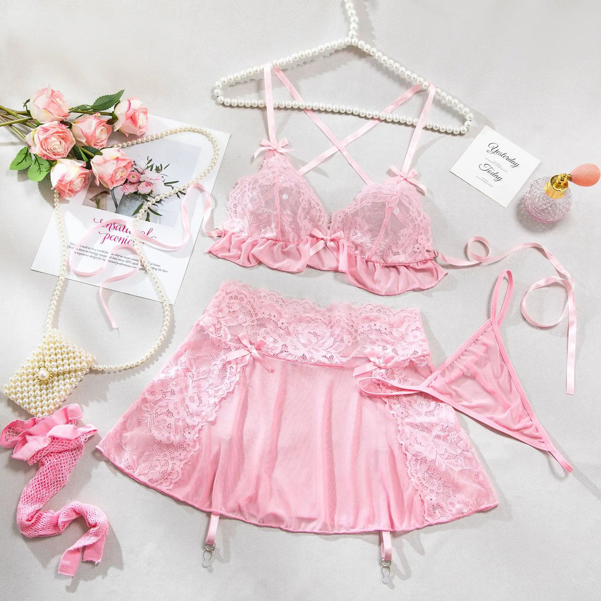 Pink lace lingerie set with accessories on a light gray background