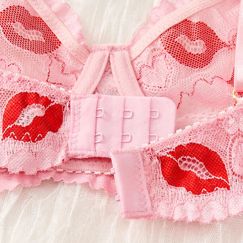 Close-up of pink lace lingerie with red heart designs on a white background