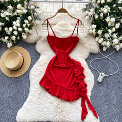 Red dress with ruffles on a white fur rug surrounded by flowers and a hat.