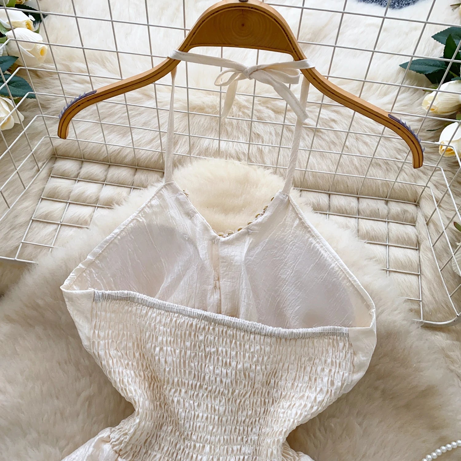 White textured top on a wooden hanger against a white grid background