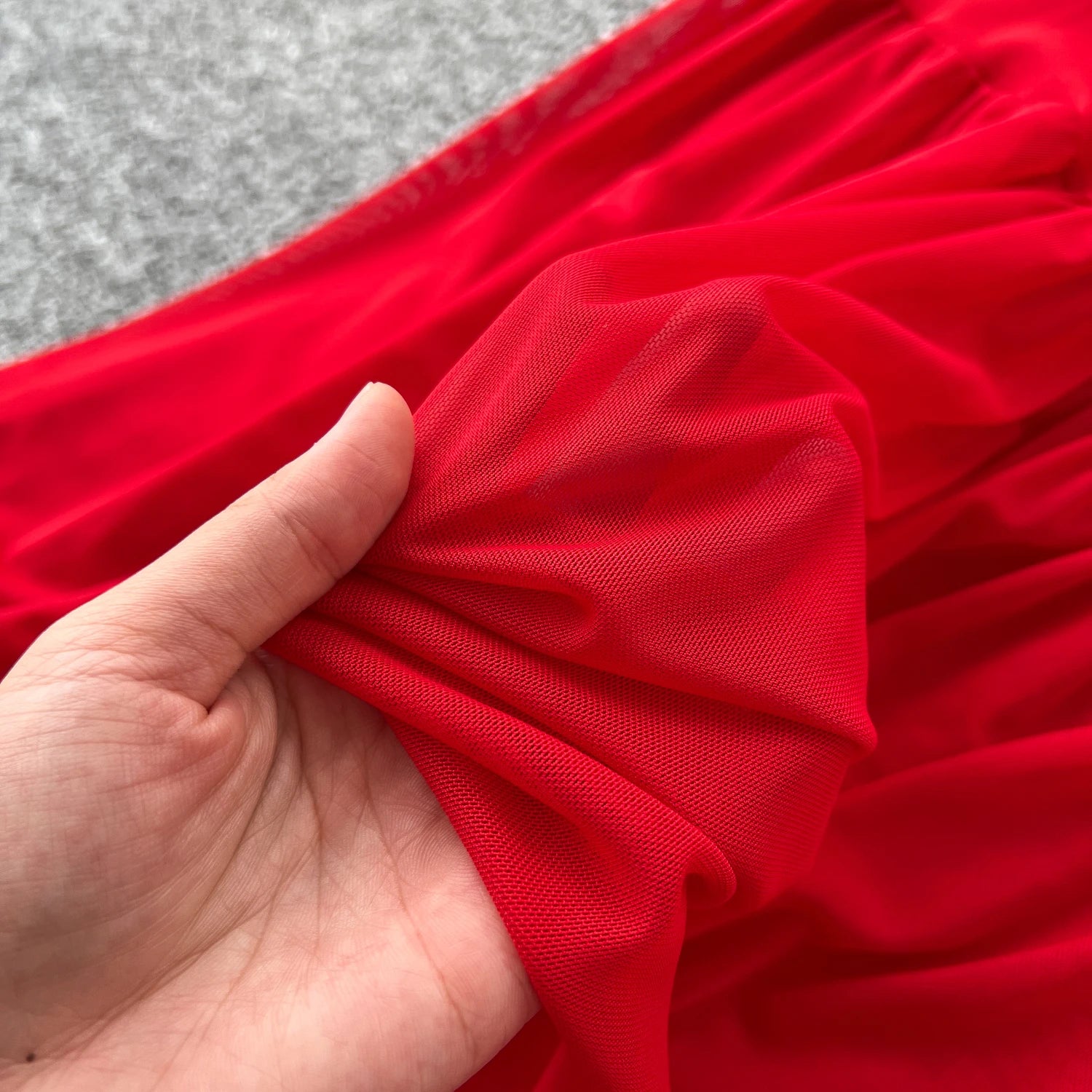 Red fabric held by a hand with a gray background