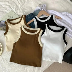 Four tank tops in beige, brown, black, and white on hangers against a light background.