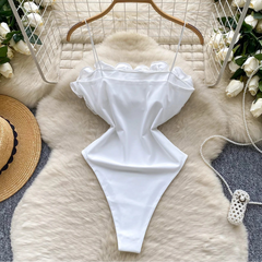 White bikini bottom on a fur surface with decorative elements like flowers and a hat.
