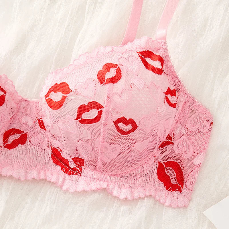 Pink lace bra with red lip prints on a white background