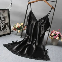 Black satin slip dress on a hanger with flowers and decor in the background