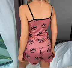 Person wearing a pink satin pajama set with black crown patterns.