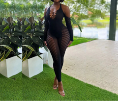 Woman in a black outfit standing outdoors with greenery and a lake in the background