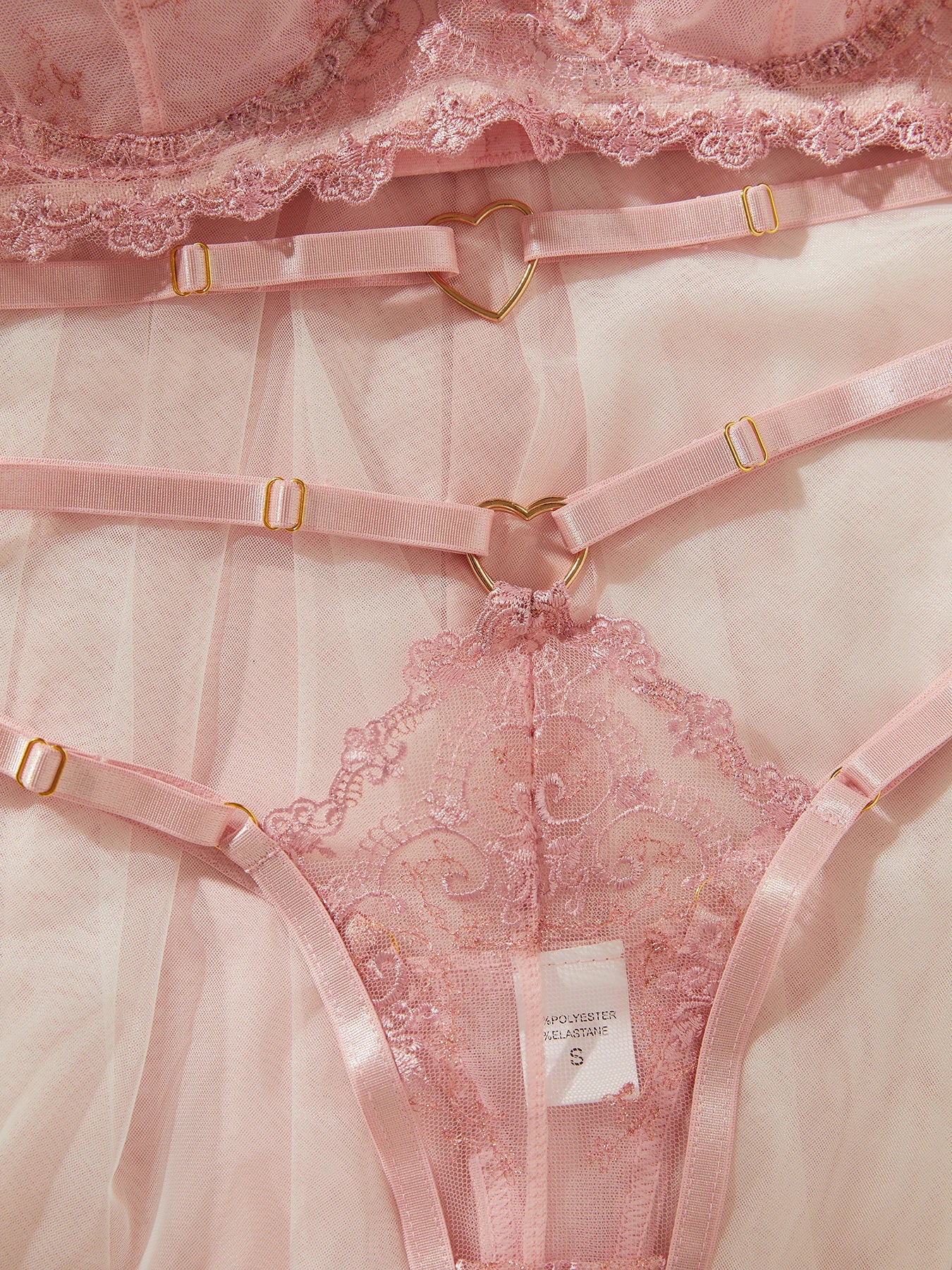 Pink lace lingerie set with a visible brand label on a light pink background
